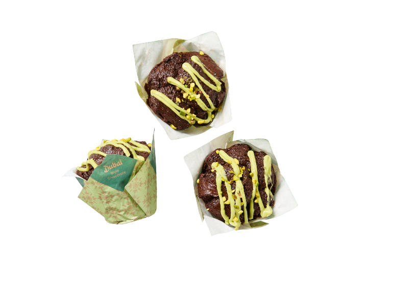 Tri čokoladna muffina sa zelenom glazurom i pistacijama, jedan u omotu 'Dubai Style Chocolate'.