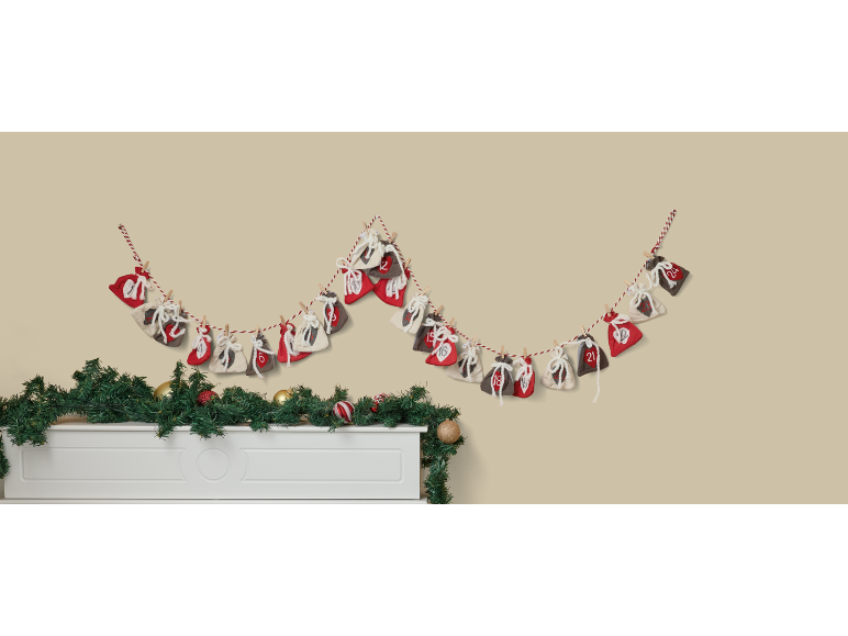 Božićni adventski kalendar s vrećicama i vijencem iznad bijelog kamina.