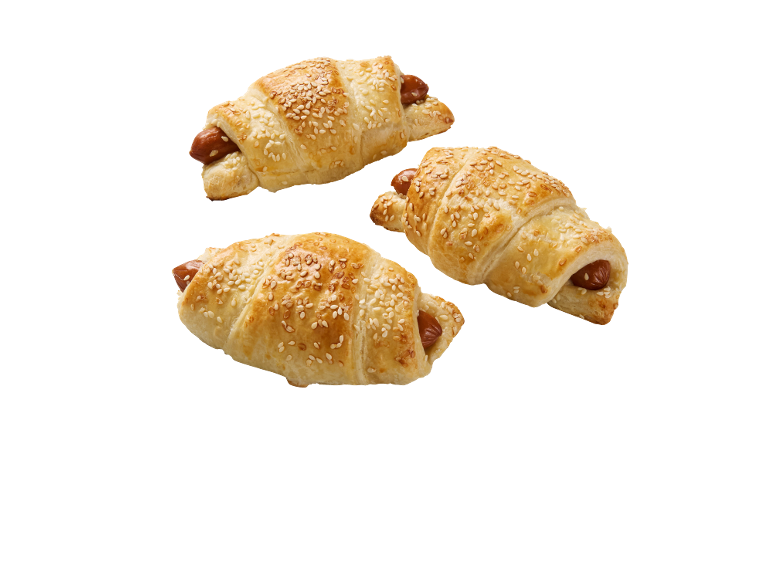 Tri slana kroasana s hrenovkom i sezamom na crnoj pozadini.