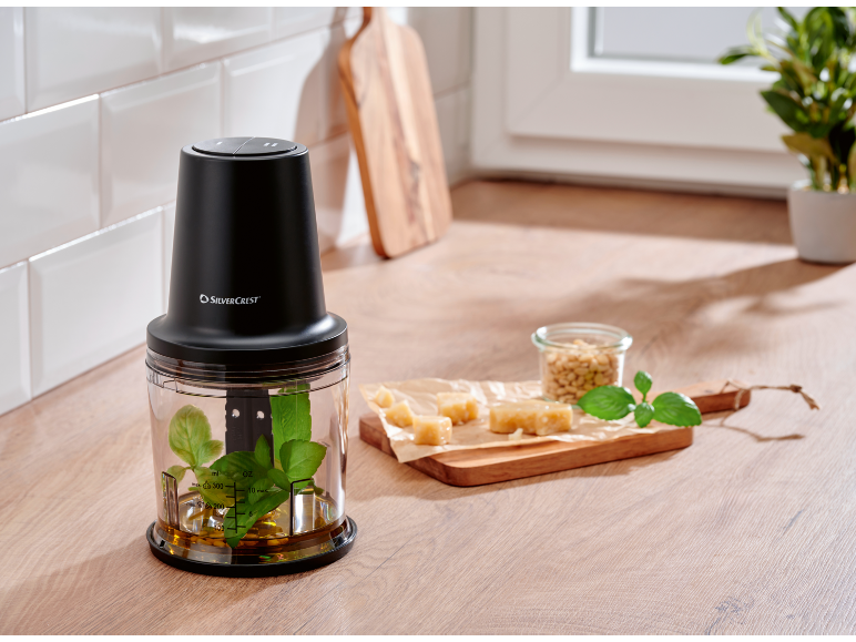 Crni sjeckalica s sastojcima za pesto na kuhinjskom pultu.