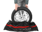 Osoba stavlja automobilsku gumu u crnu torbu za pohranu s crvenom prugom.