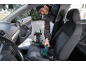 Muškarac čisti sjedalo automobila usisavačem za mokro i suho usisavanje.