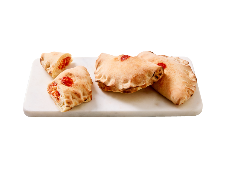 Četiri pečene calzone, punjene rajčicom i sirom, na bijeloj mramornoj dasci.