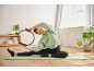 Žena u CRIVIT majici i tajicama vježba s pilates prstenom na prostirci.