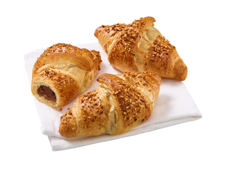 Tri kroasana s orasima, jedan punjen čokoladom, na bijelom ubrusu.