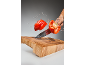 Crvena paprika se reže u zraku s prskanjem vode iznad drvene daske za rezanje.