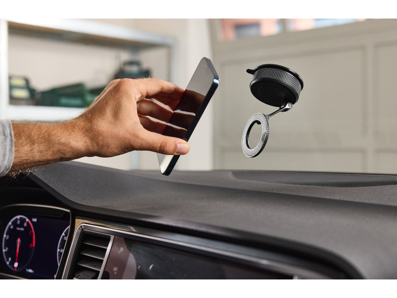 Muška ruka drži pametni telefon blizu držača za automobil s vakuumskom čašicom.