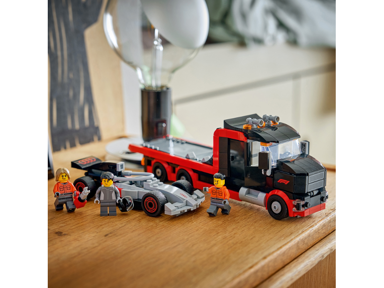 Set za izgradnju trkaćeg kamiona i bolida Formule 1 s figurama na drvenom stolu.