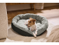 Pas Jack Russell terijer leži u sivom, plišanom krevetu za kućne ljubimce na tepihu.