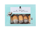 Kutija kokosovih petit four kolačića s punjenjem od marelice, djelomično umočenih u čokoladu.