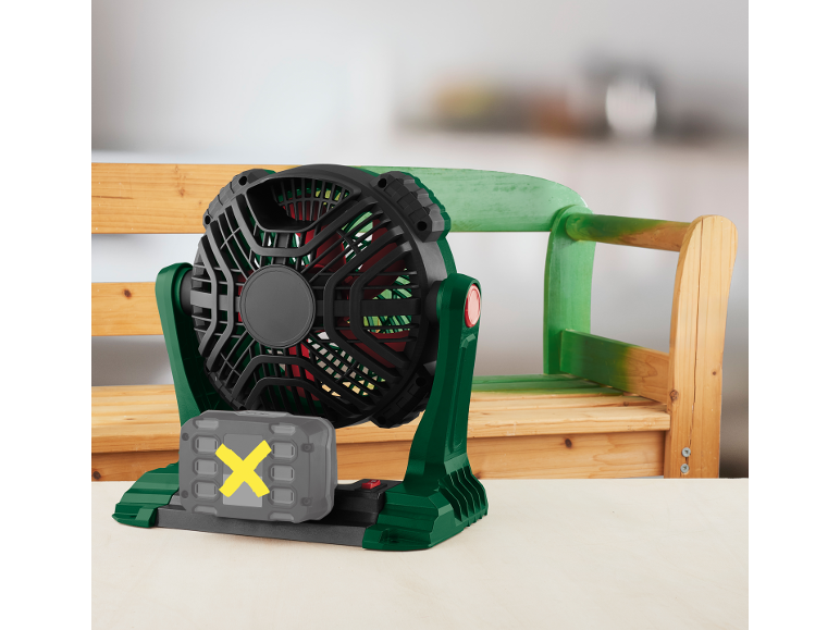 Zeleno-crni ventilator na baterije sa sivom baterijom sa žutim X, suši zeleno obojanu drvenu stolicu.