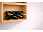 Drvena zidna polica s crnim stalkom za vino koji sadrži boce vina.