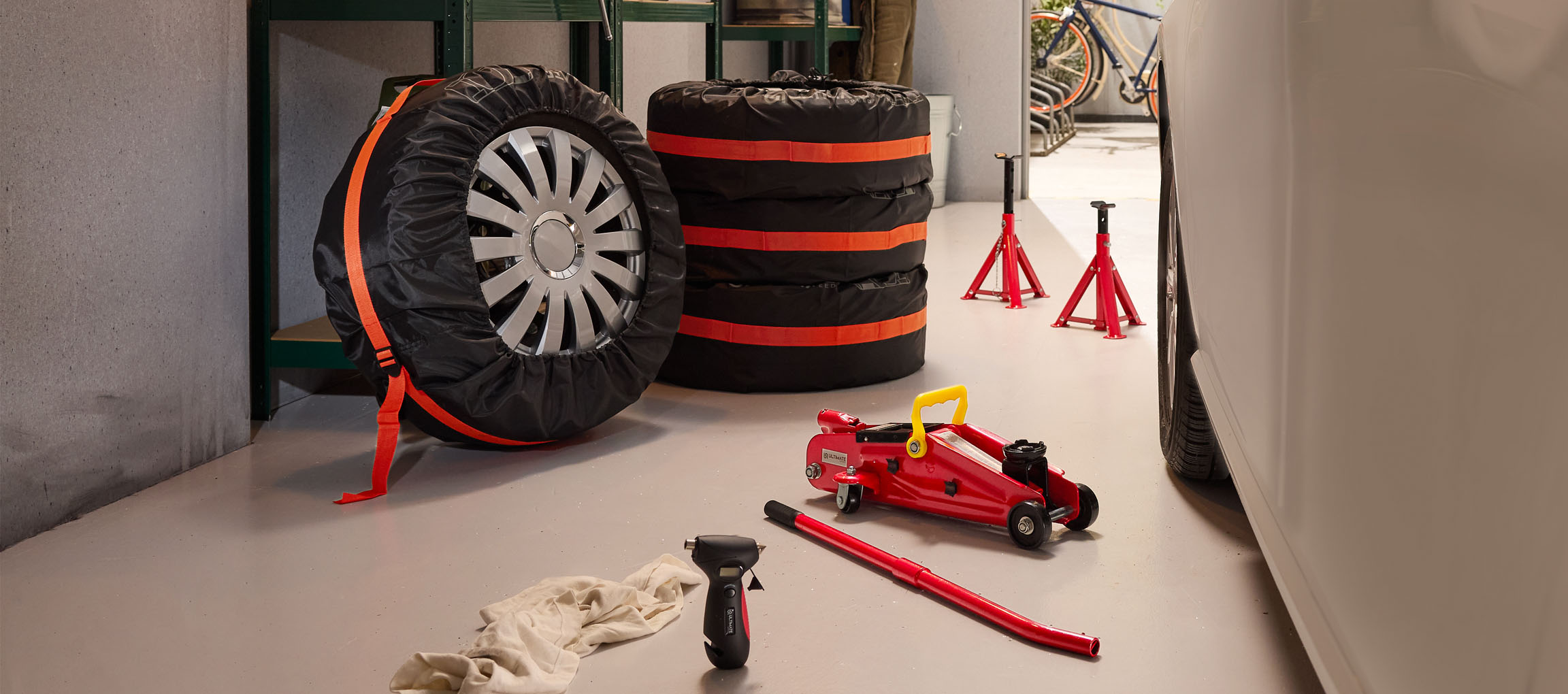 Automobilske gume s navlakama, dizalica i stalci u garaži.