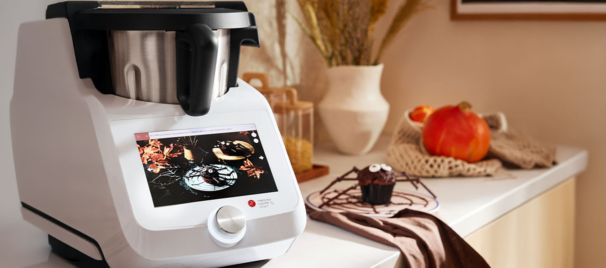 Kuhinjski robot s dodirnim zaslonom prikazuje recept za Noć vještica, pored muffina-pauka.