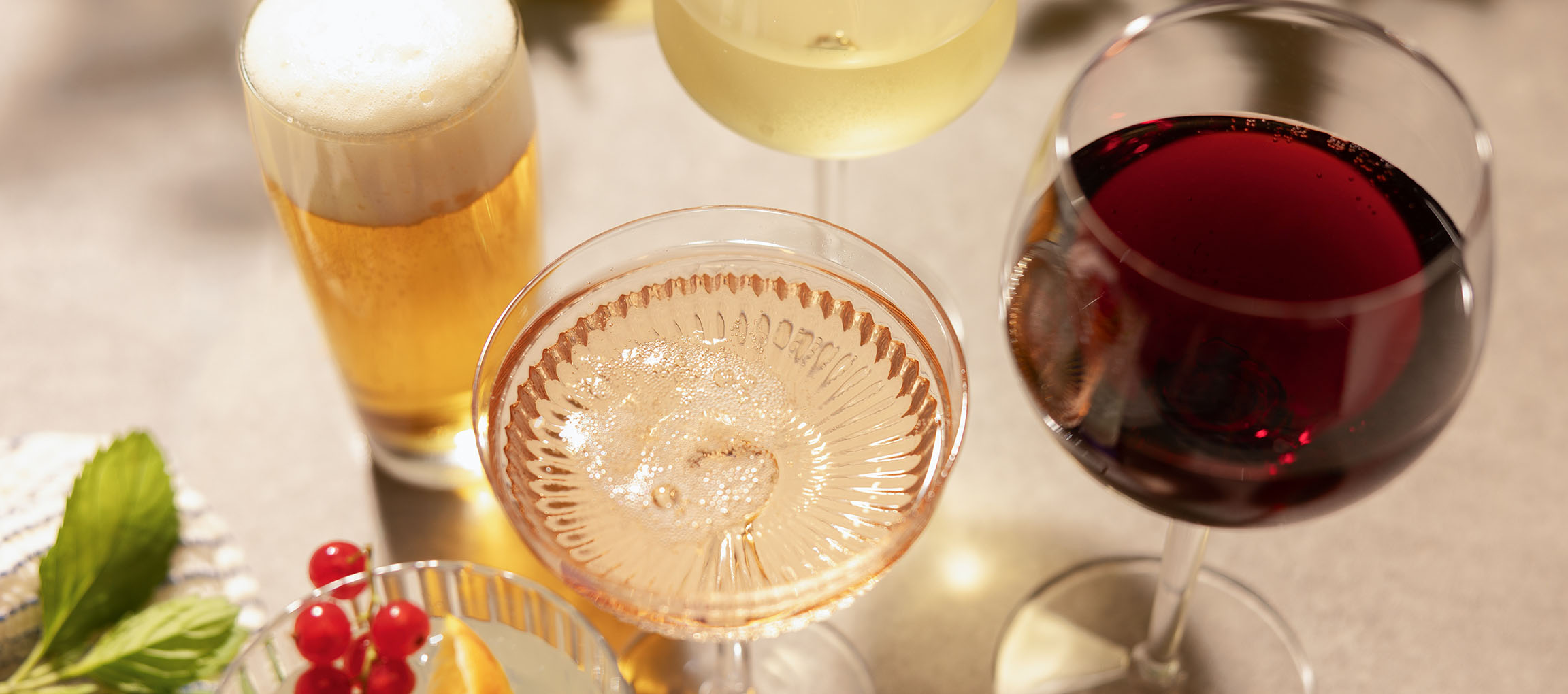Pivo, rose vino i crno vino u čašama, s bobicama i mentom.