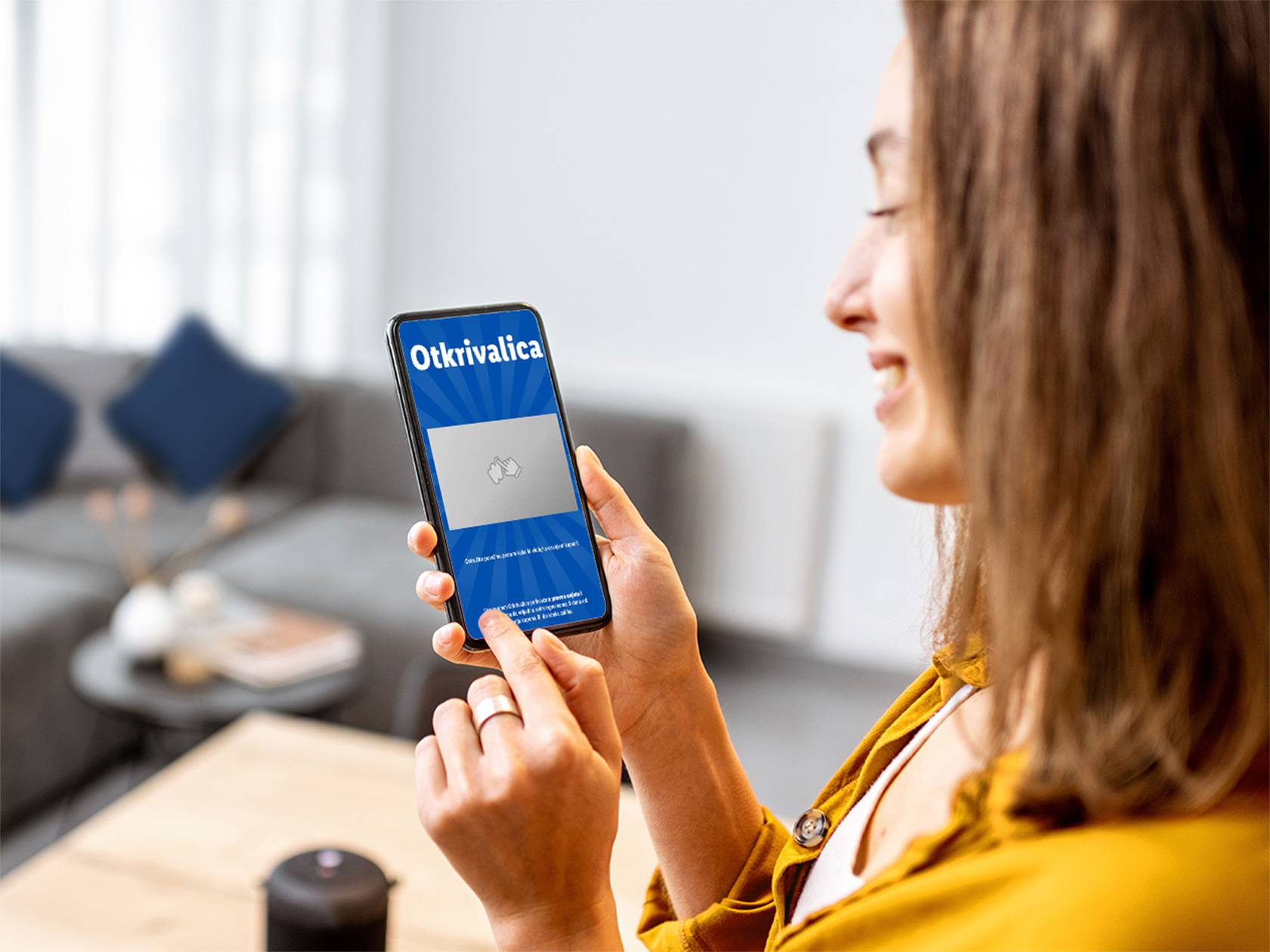 Žena koristi pametni telefon s aplikacijom 'Otkrivalica' u dnevnoj sobi.