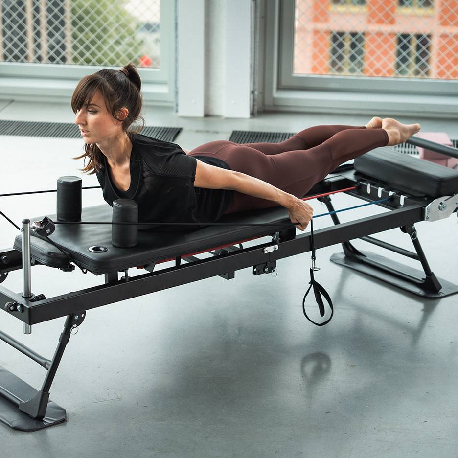Žena vježba na Pilates spravi s trakama otpora.