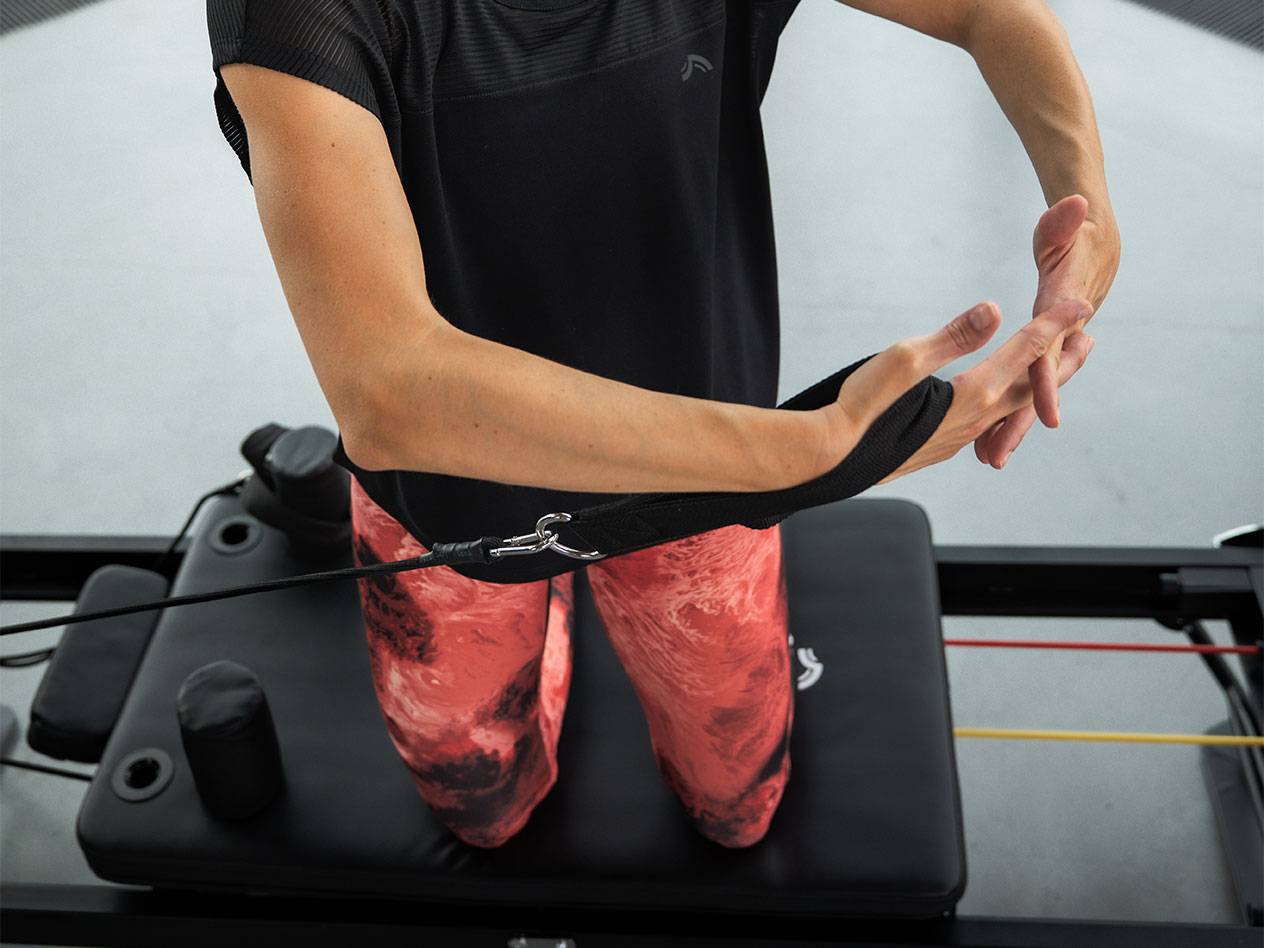 Žena vježba s trakama otpora na Pilates spravi.