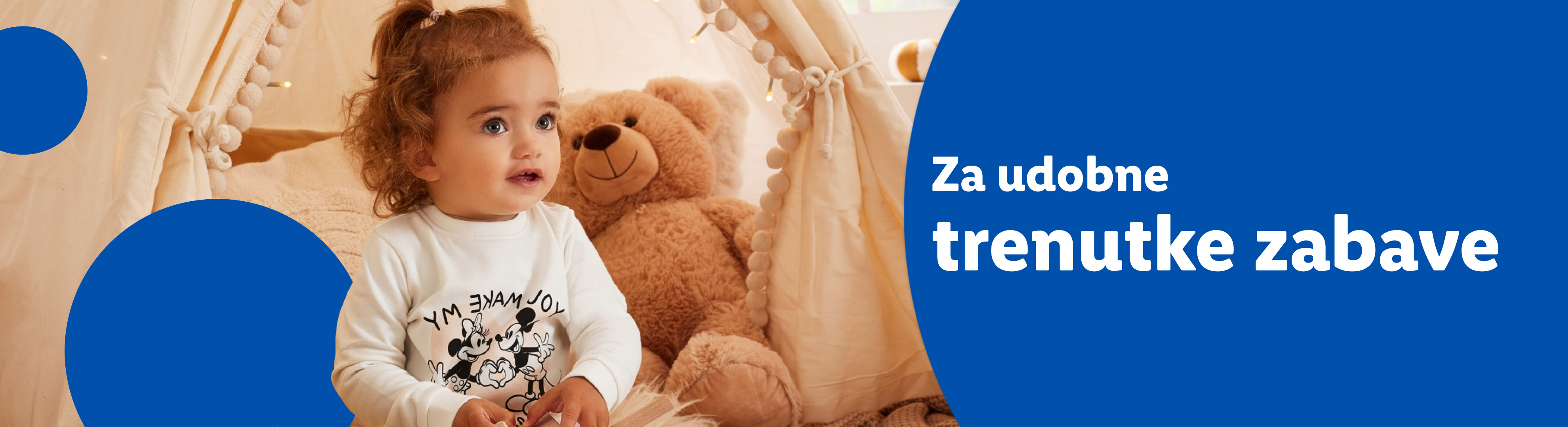 Dijete u šatoru za igru s plišanim medvjedićem i natpisom: „Za udobne trenutke zabave”.