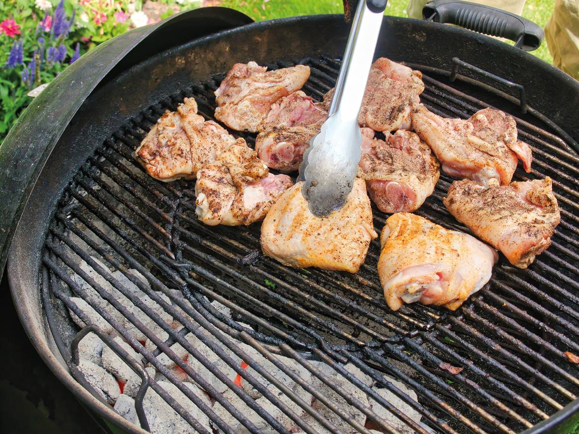 Piletina na roštilju s hvataljkama, spremna za pečenje.