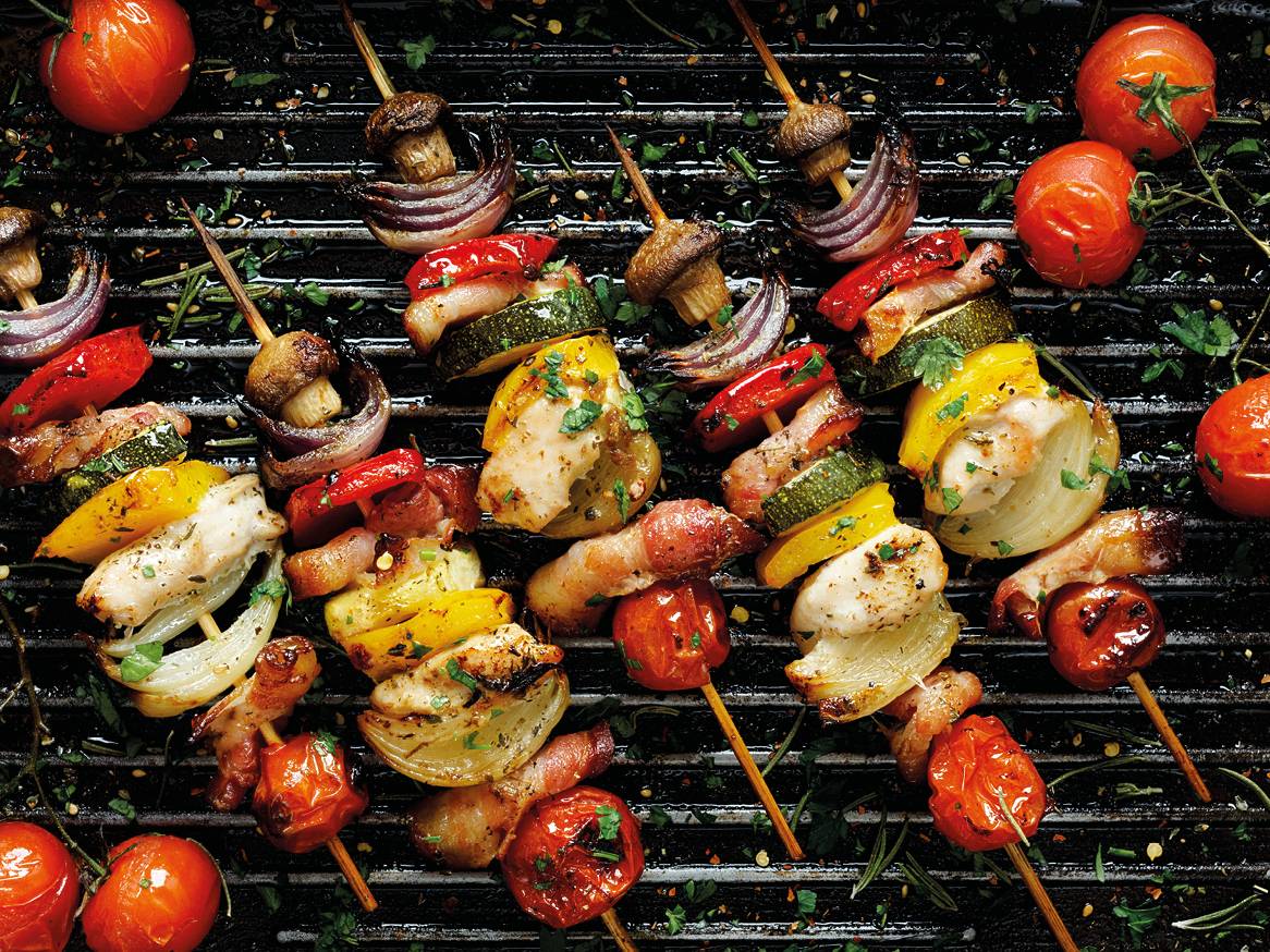 Roštilj s ražnjićima od piletine, povrća i slanine, s rajčicama i gljivama.