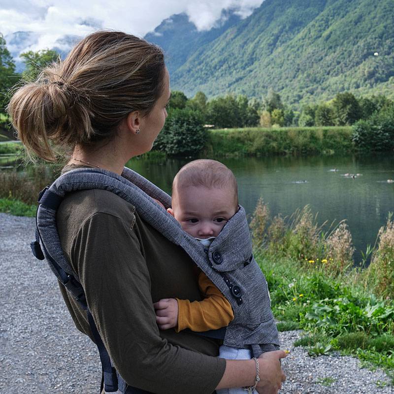 Majka s bebom u nosiljci na otvorenom.
