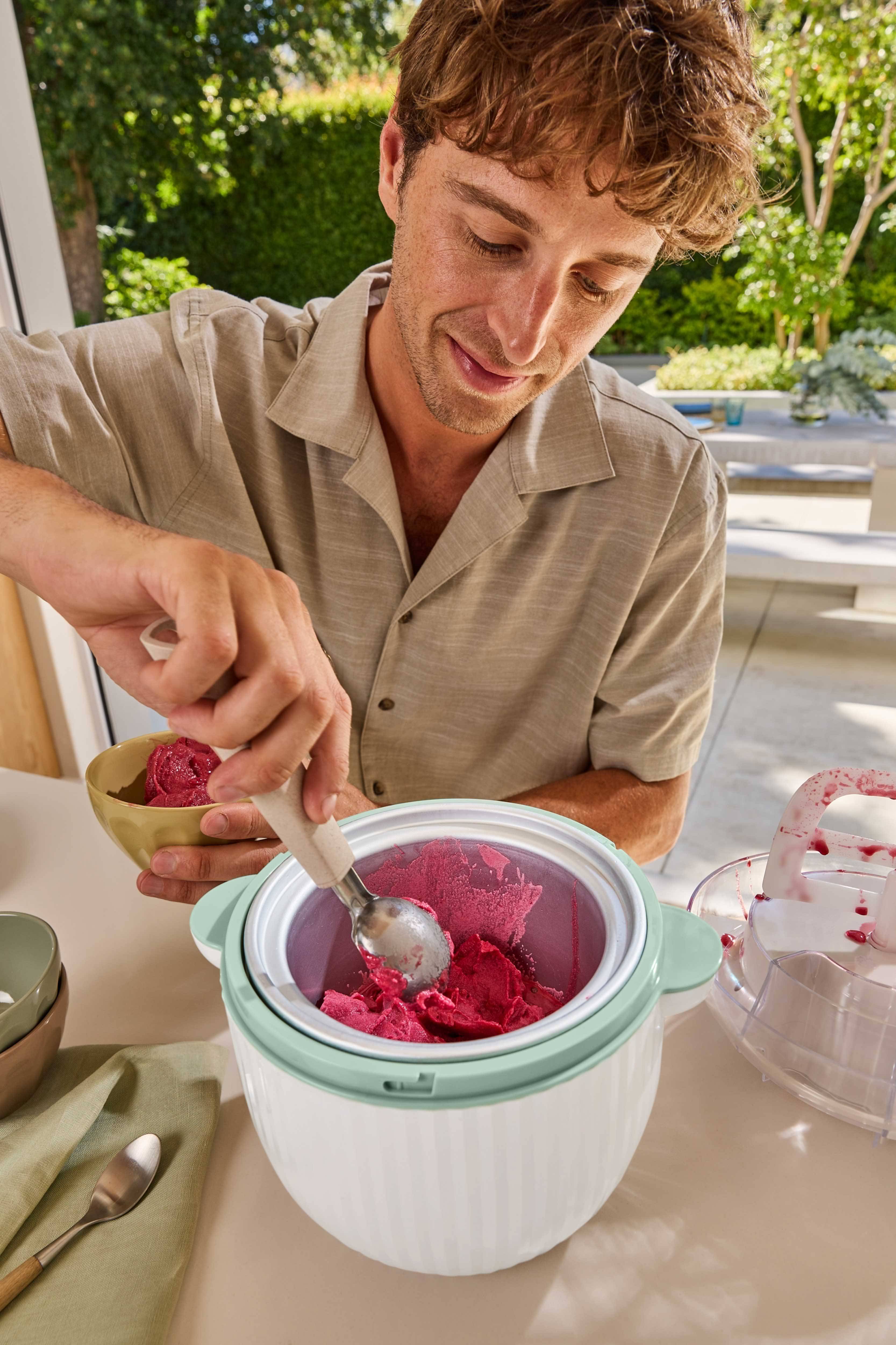Muškarac vadi crveni sorbet iz aparata za sladoled u zdjelu.