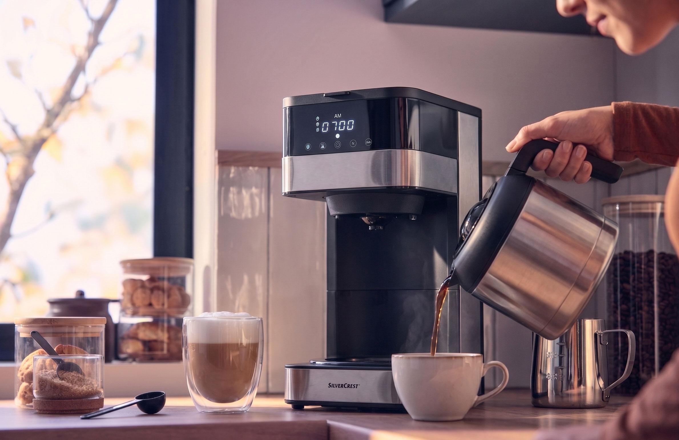 Aparat za kavu toči kavu u šalicu, s latteom i kolačićima na pultu.