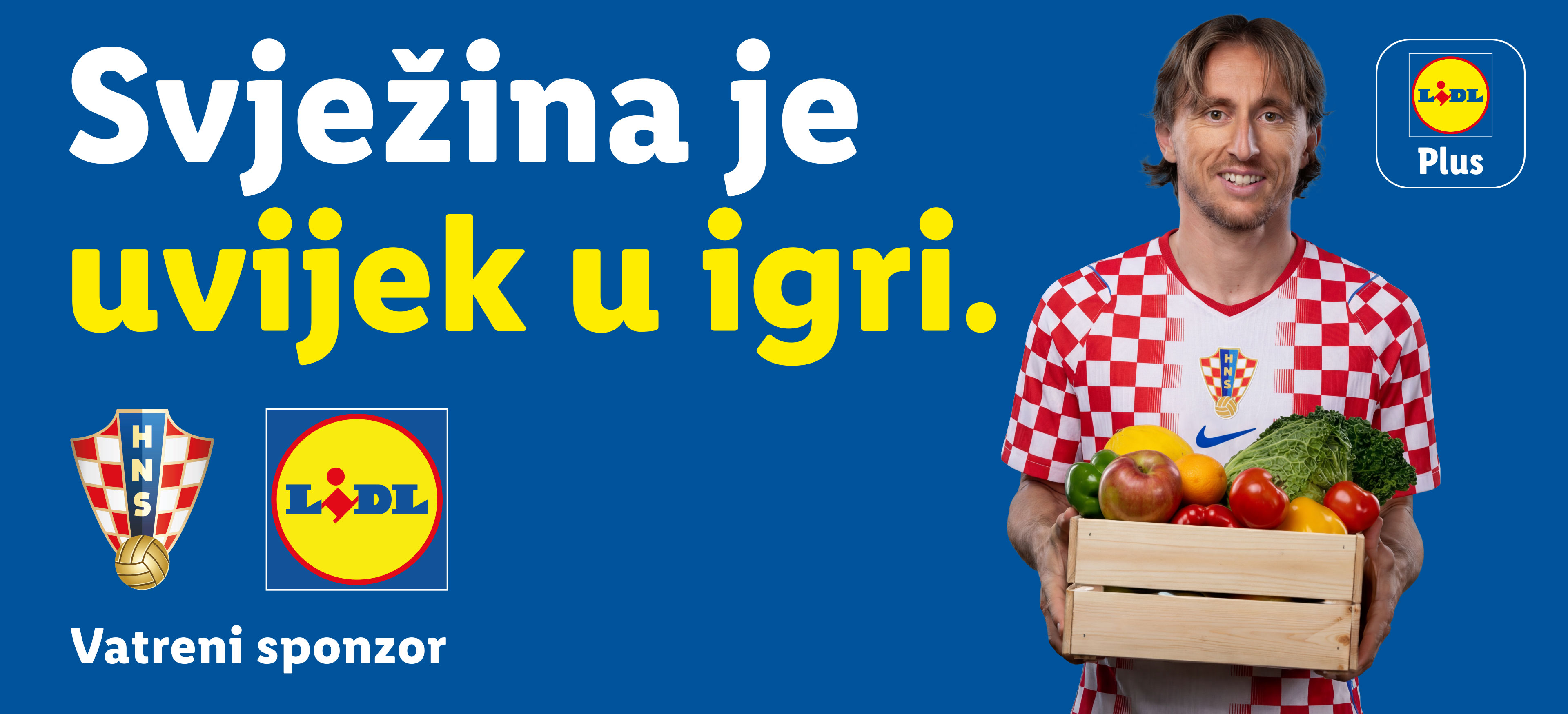 Nogometaš drži sanduk svježeg voća i povrća, s natpisom 'Svježina je uvijek u igri'.