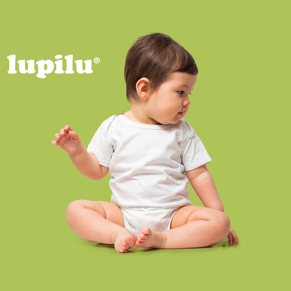 Beba u bijelom bodiju sjedi na zelenoj pozadini, gleda udesno, s logotipom dječje odjeće.