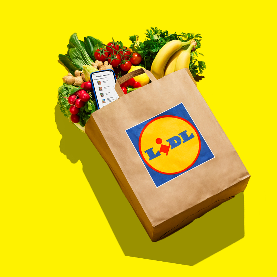 Papirnata vrećica s namirnicama poput rajčica, banana, rotkvica i mobitelom na žutoj pozadini.