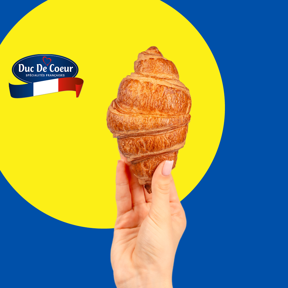 Ruka drži croissant na žutoj pozadini s plavim rubom i francuskom zastavom.
