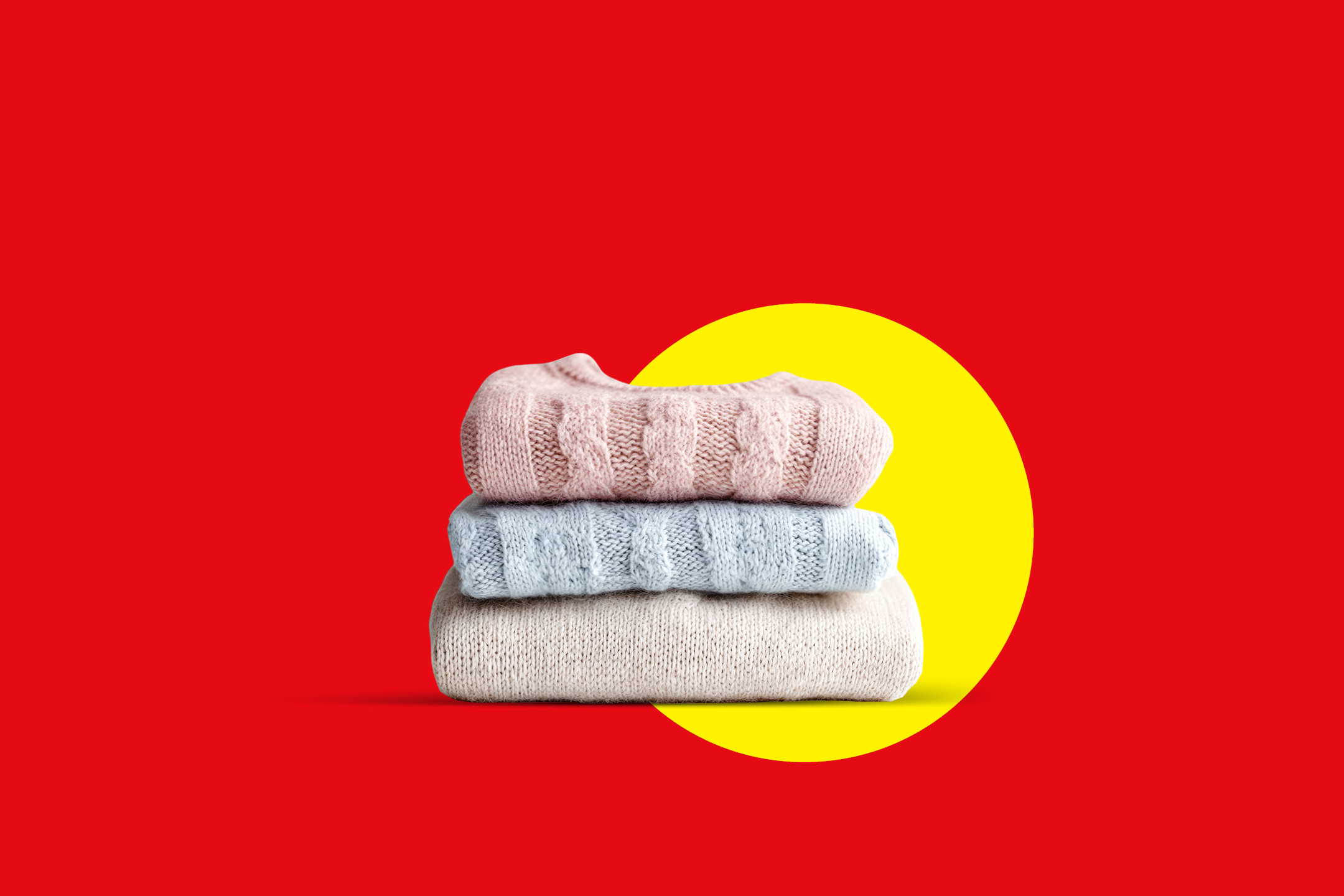 Složeni džemperi u ružičastoj, plavoj i bež boji na crvenoj pozadini sa žutim krugom.