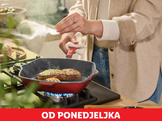 Osoba posipa začine po odresku u tavi na plinskom štednjaku.