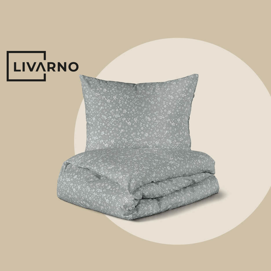 Sivi set posteljine s cvjetnim uzorkom, jastuk i presavijena poplun.