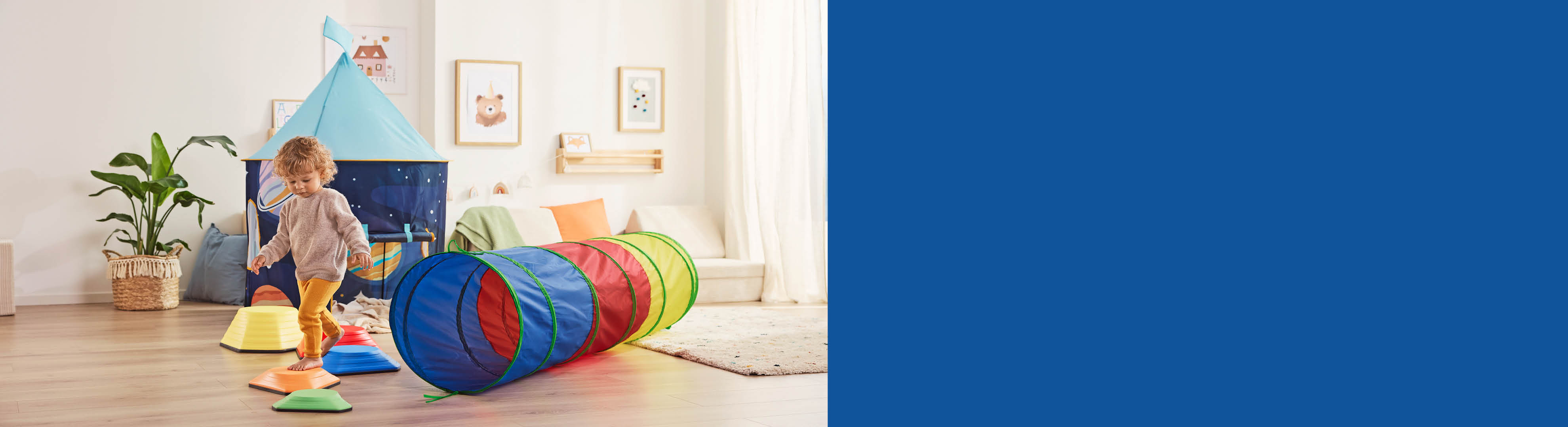 Dijete se igra s tunelom za puzanje i balansirnim kamenjem u dječjoj sobi.