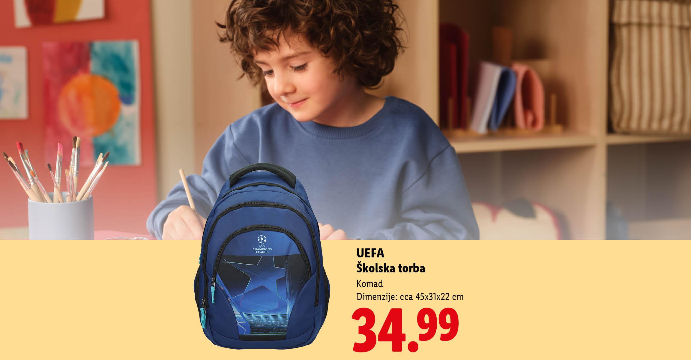 Dječak slika za stolom, pored njega je plavi školski ruksak s cijenom od 34,99.