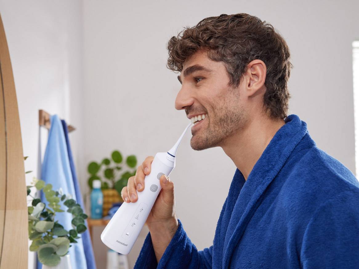 Muškarac koristi Oral-B vodeni čistač zuba u kupaonici.