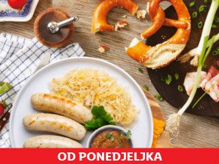 Tanjur s kobasicama i kiselim kupusom, pereci i slanina na drvenom stolu.
