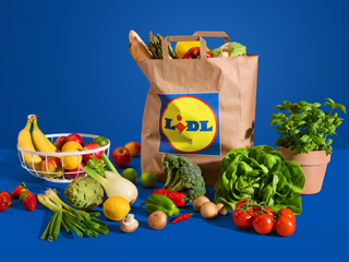 Lidl papirnata vrećica puna namirnica okružena svježim voćem i povrćem na plavoj pozadini.