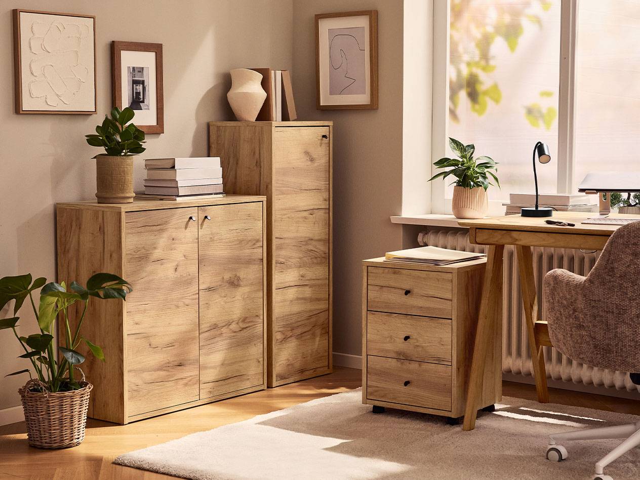 Kućni ured sa svijetlim drvenim ormarićima, uredskom stolicom i stolnom lampom.