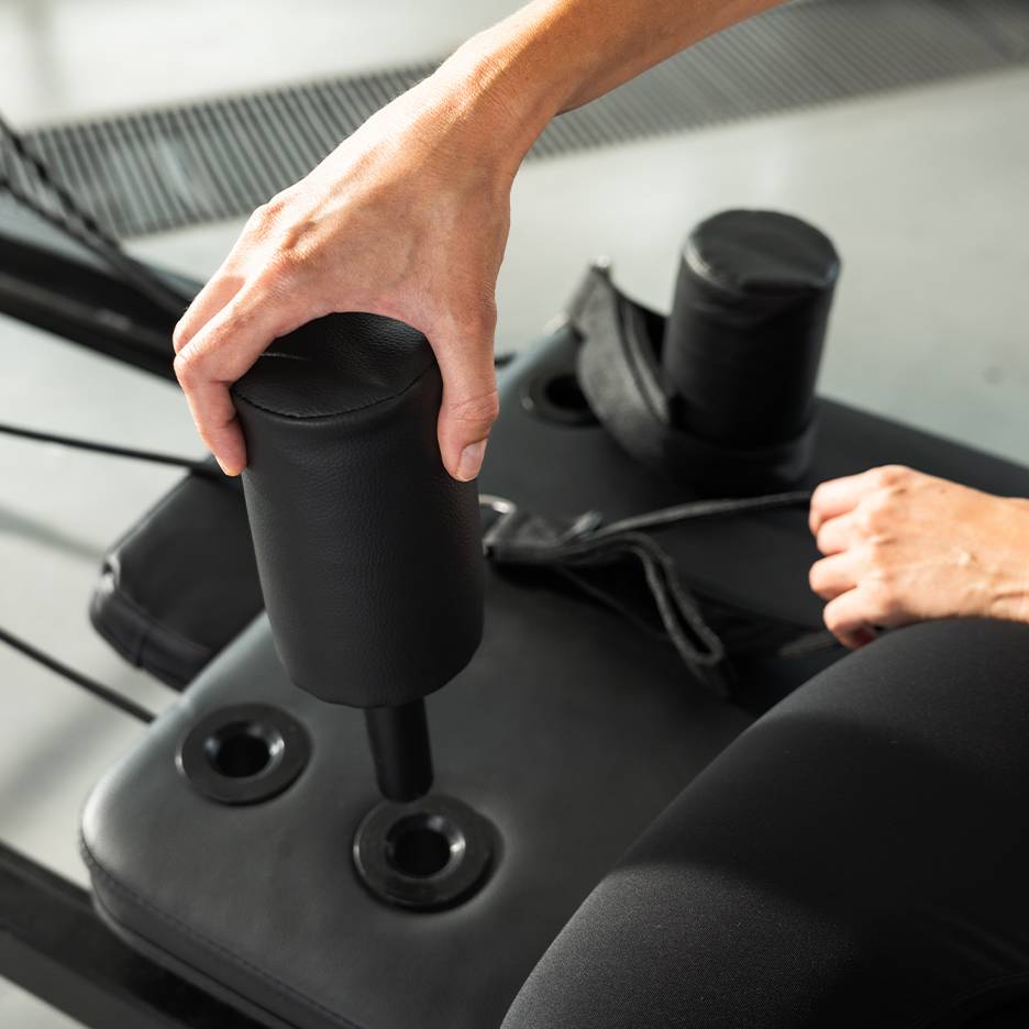 Osoba podešava crnu podstavljenu spravu za vježbanje.