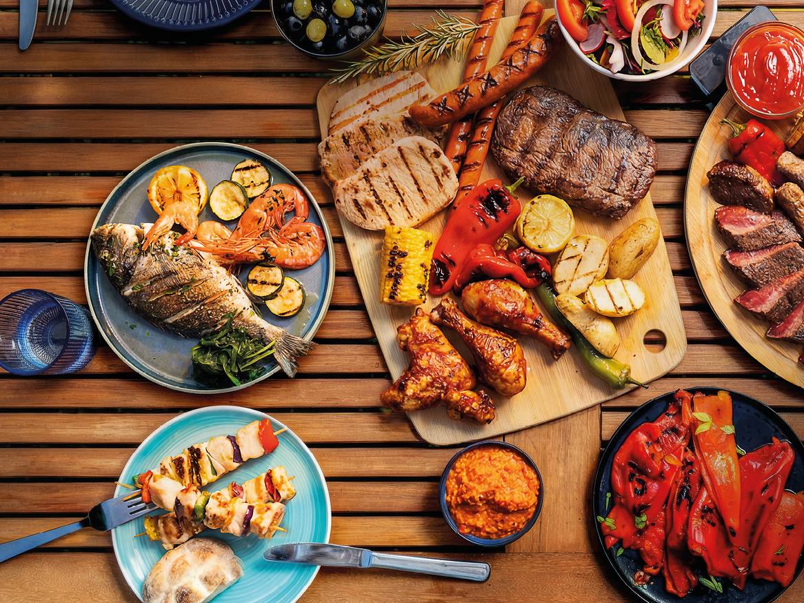 Roštilj s mesom, ribom, plodovima mora, povrćem i umacima na drvenom stolu.