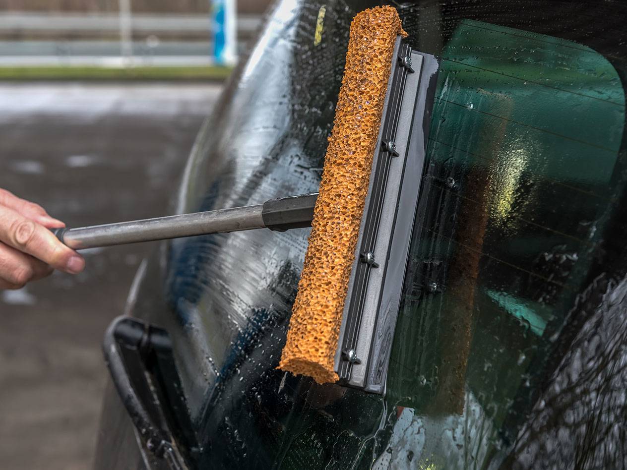 Čistač prozora s dugom ručkom čisti stražnje staklo automobila.