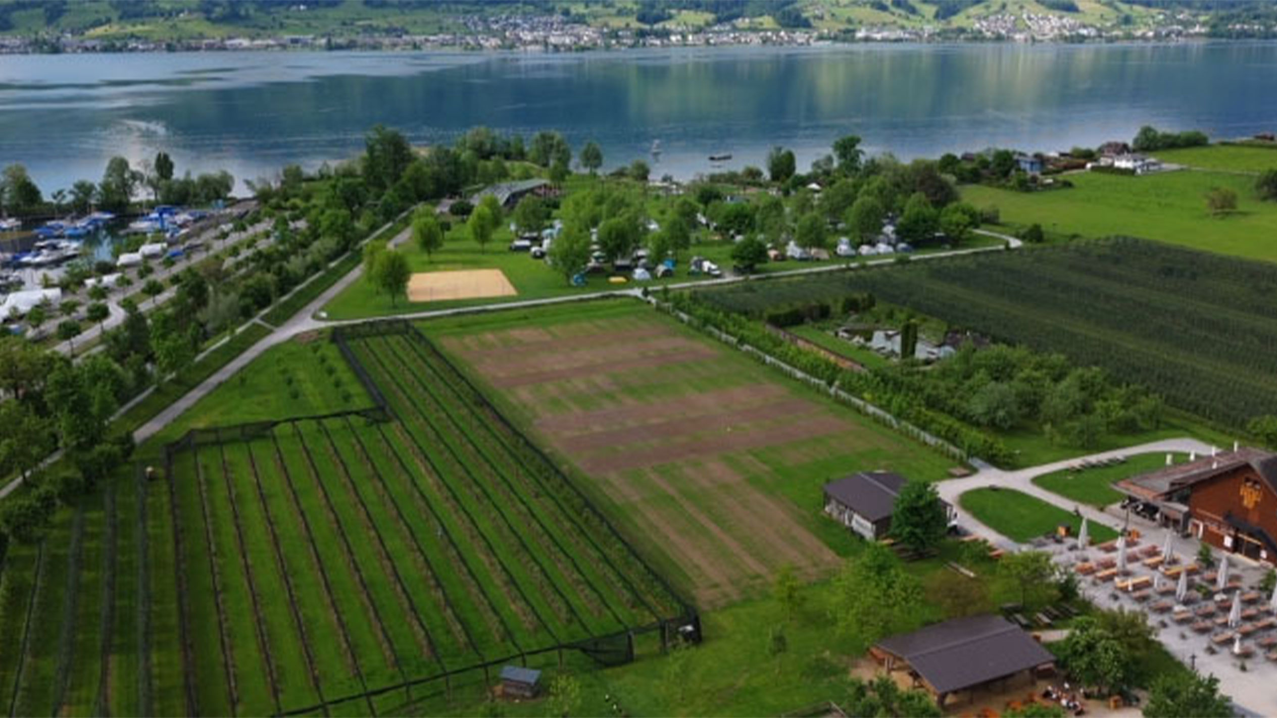 Zračna snimka kampa uz jezero, s vrtovima i restoranom.
