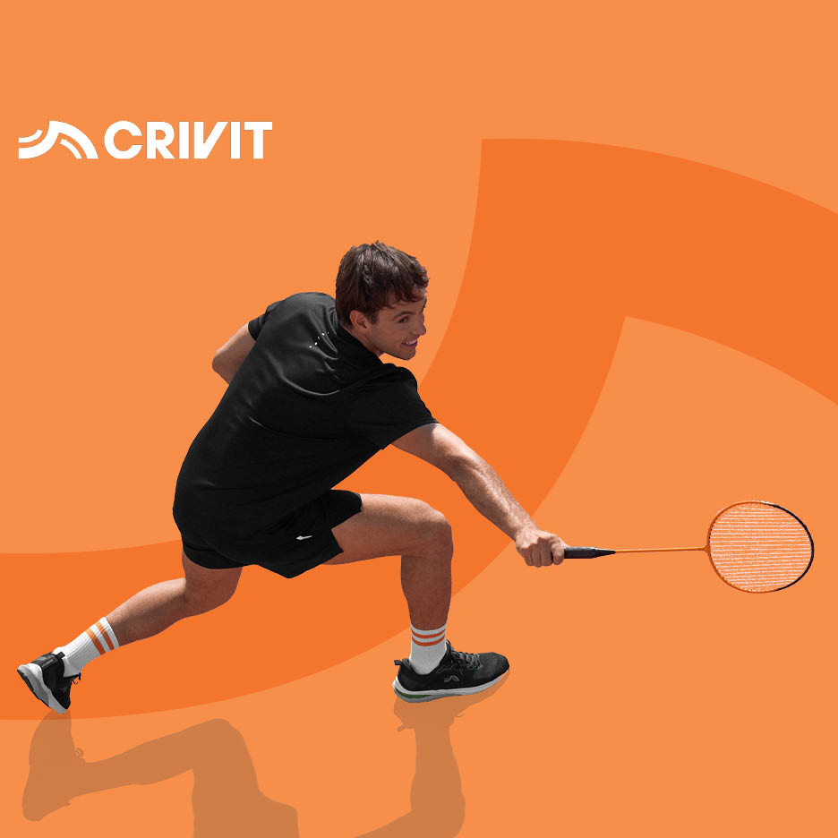 Muškarac u crnoj sportskoj odjeći igra badminton s narančastim reketom.