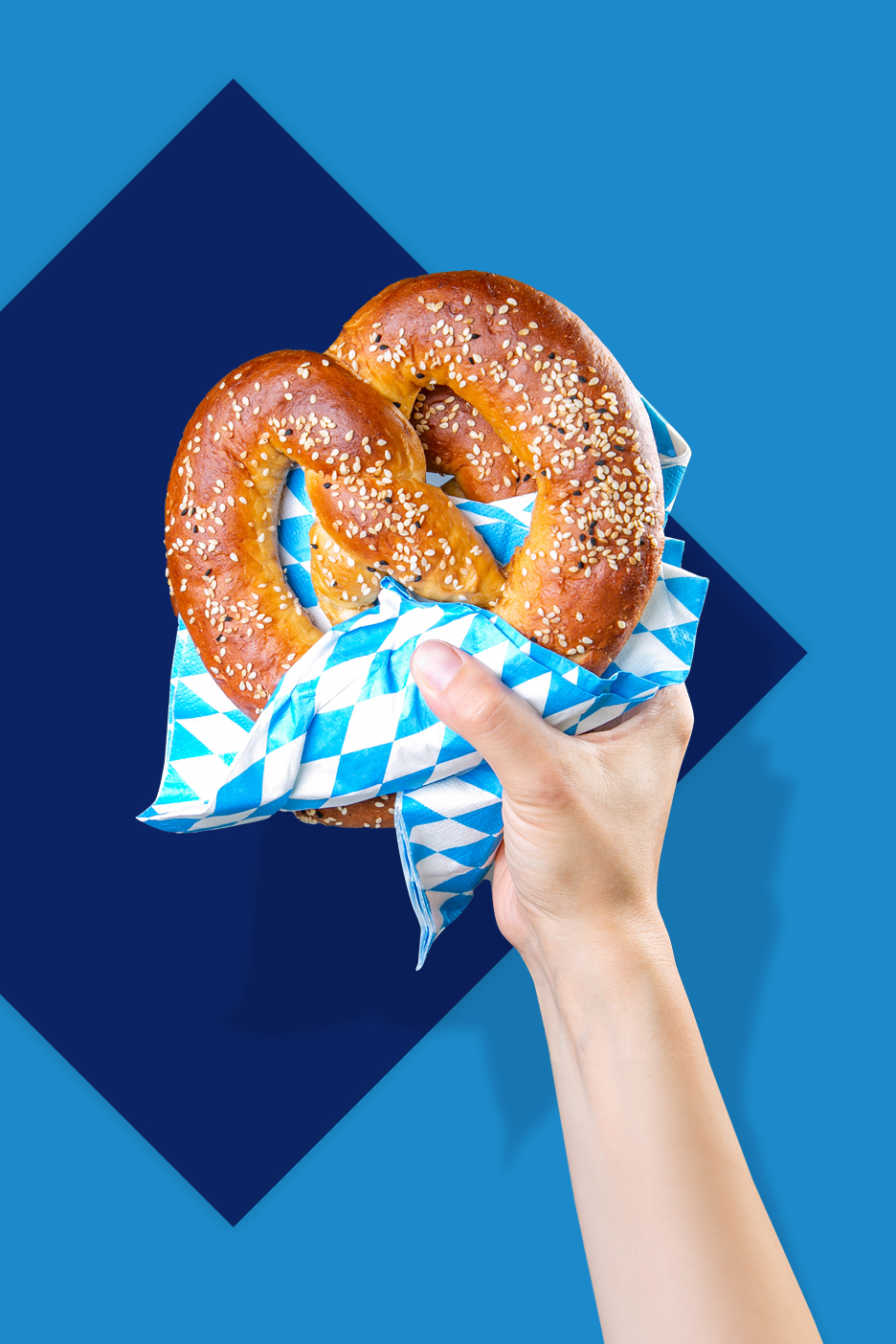 Ruka drži perec umotan u plavo-bijelu kariranu salvetu na plavoj pozadini.