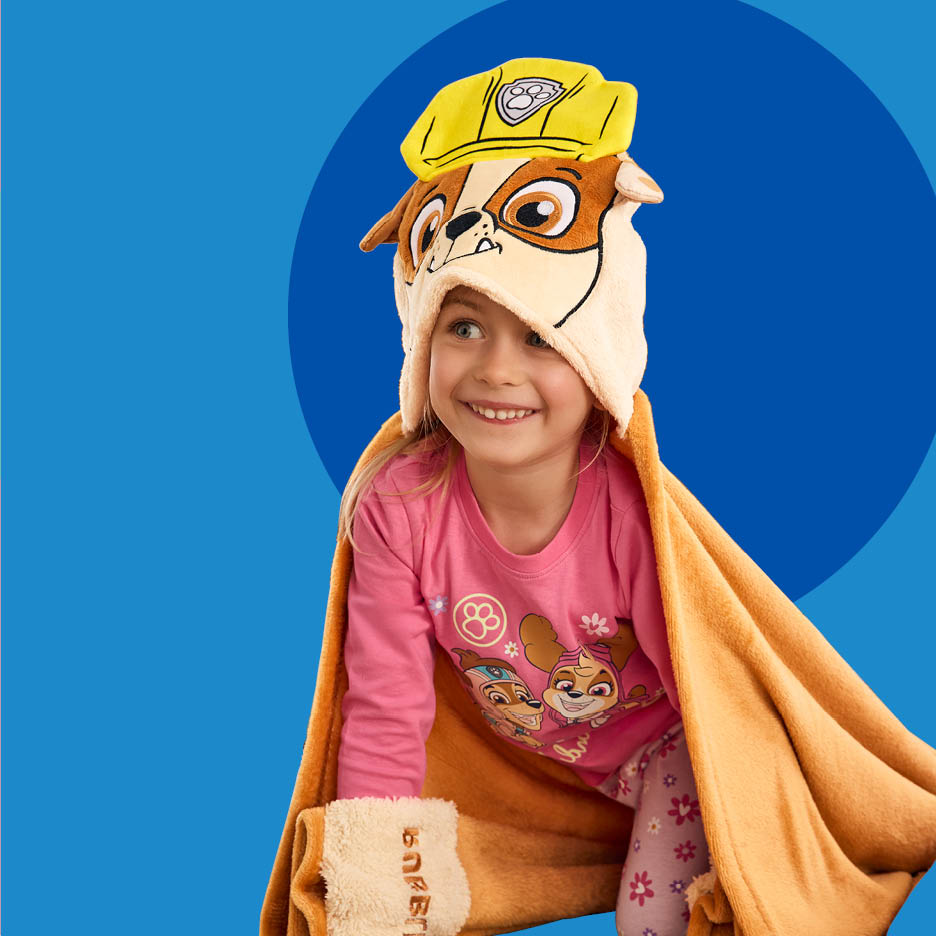 Djevojčica u žutoj Paw Patrol Rubble dekici s kapuljačom i ružičastoj pidžami.