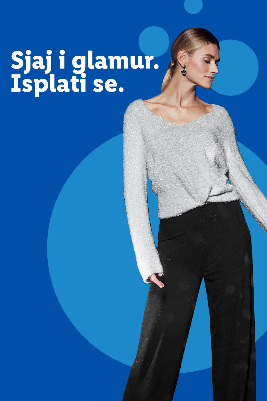 Žena u sivom pletenom džemperu i crnim hlačama na plavoj pozadini.