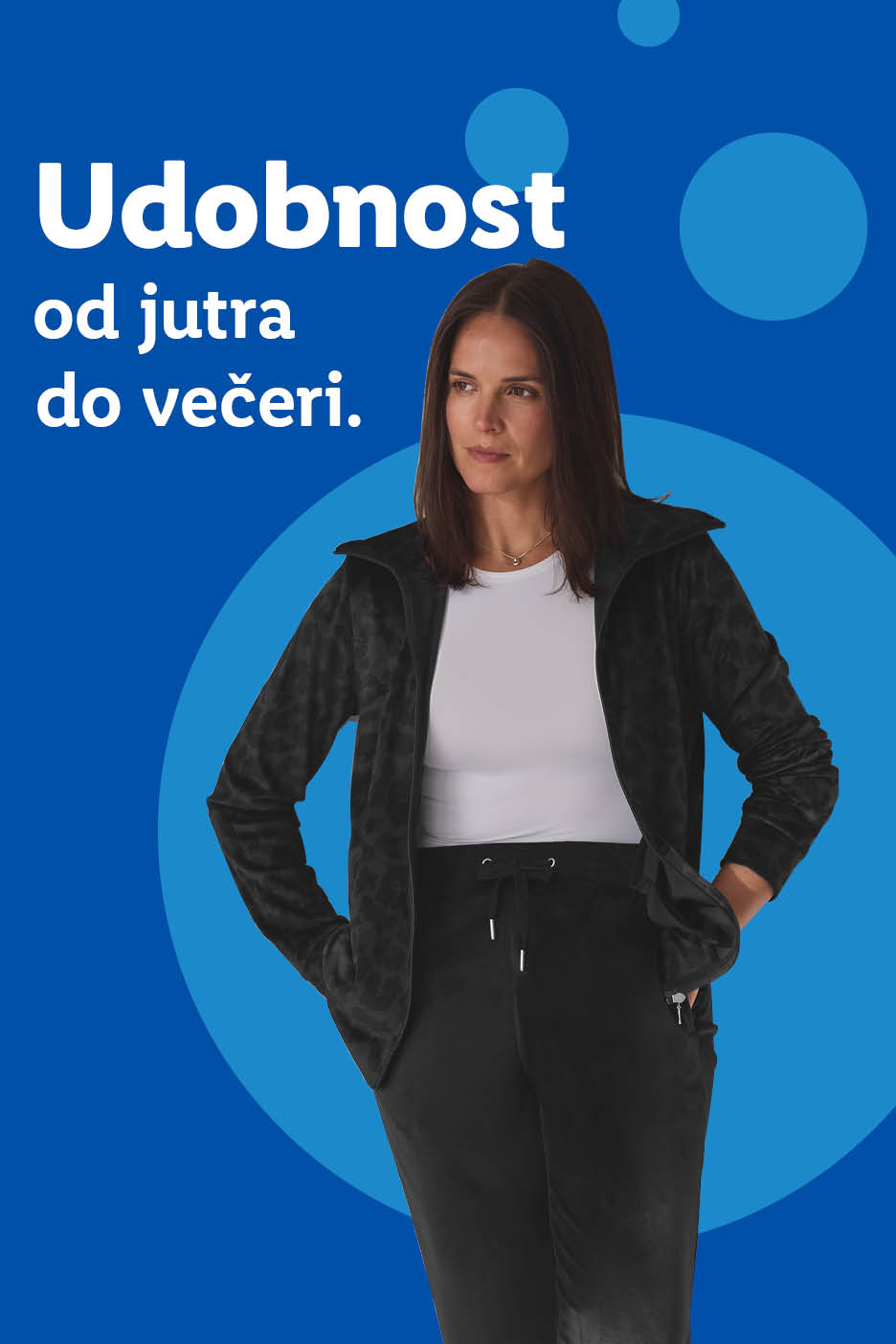 Žena u crnoj trenirci i bijeloj majici s natpisom 'Udobnost od jutra do večeri'.